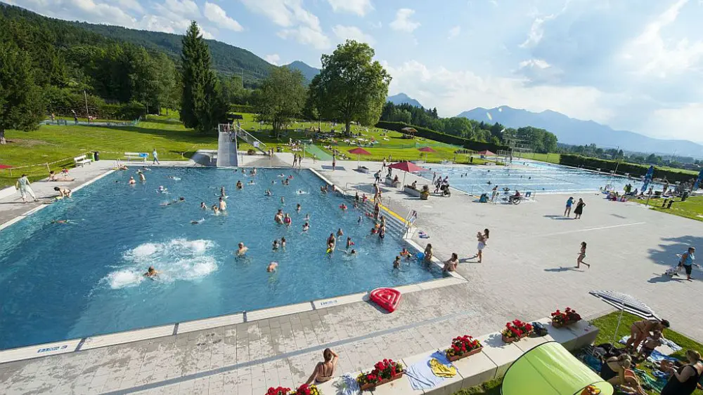 Die Schwimmbecken des Alpenwarmbads Benediktbeuern mit Liegewiese im Hintergrund