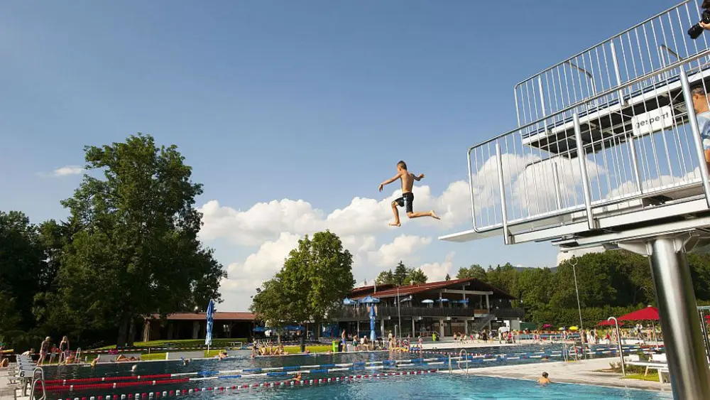 Kind springt vom Sprungturm im Alpenwarmbad Benediktbeuern