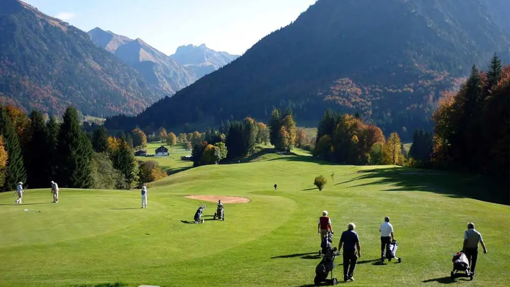 Eine Gruppe Golfer zieht ihre Trolleys über den Golfplatz des Golfclubs Oberstdorf