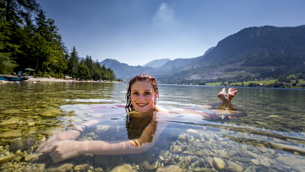 Eine Frau erfrischt sich im glasklaren Grundlsee