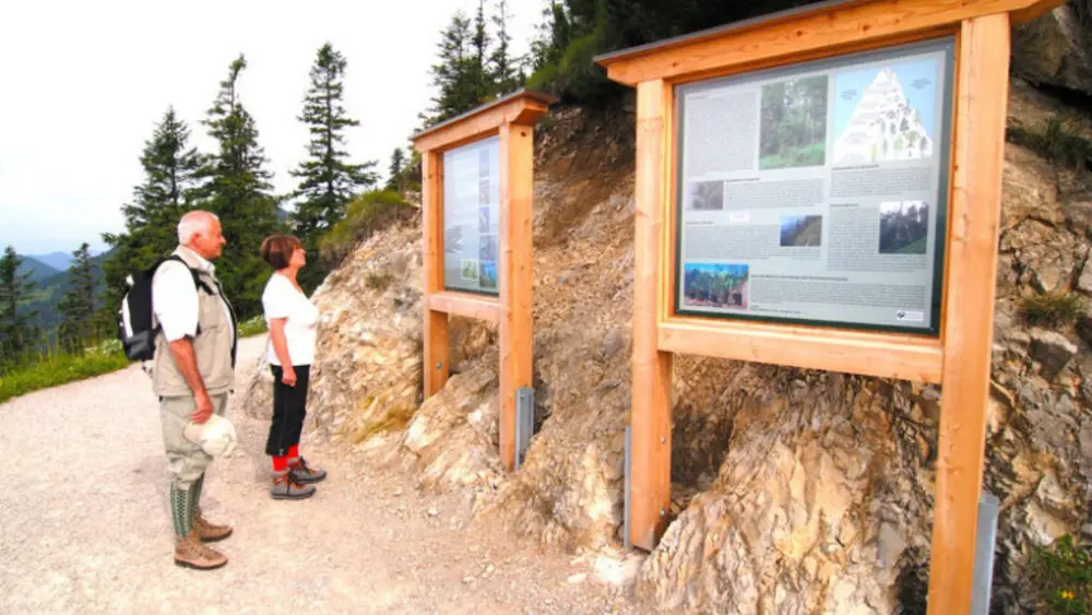 Wanderer an Informationstafeln des Naturerlebnispfads am Herzogstand