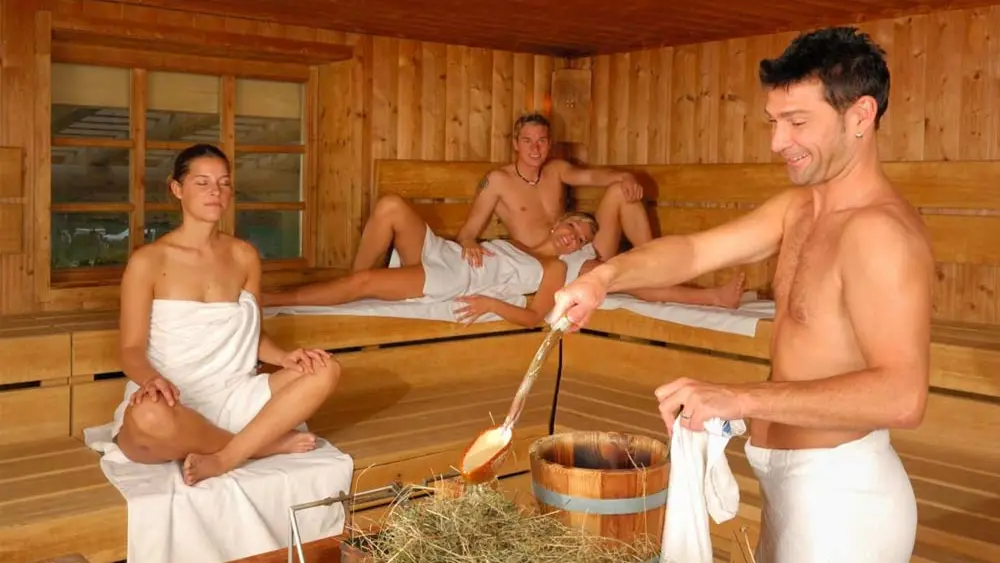 Gäste der Alpensauna machen einen Heu-Aufguss in der Oberstdorf Therme
