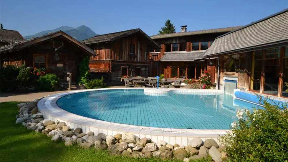Blick auf das Außenbecken der Oberstdorf Therme, im Hintergrund das Saunadorf