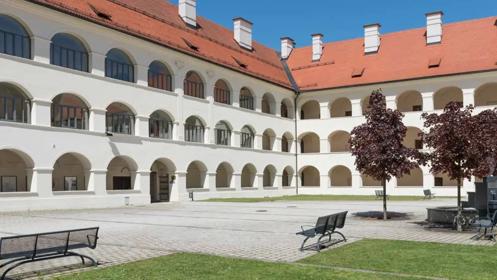 Arkadenhof des Stifts Eberndorf mit Bäumen und Bänken