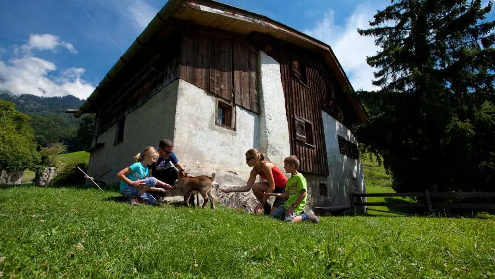 Familie mit Ziege vor der Hütte im Heididorf Maienfeld