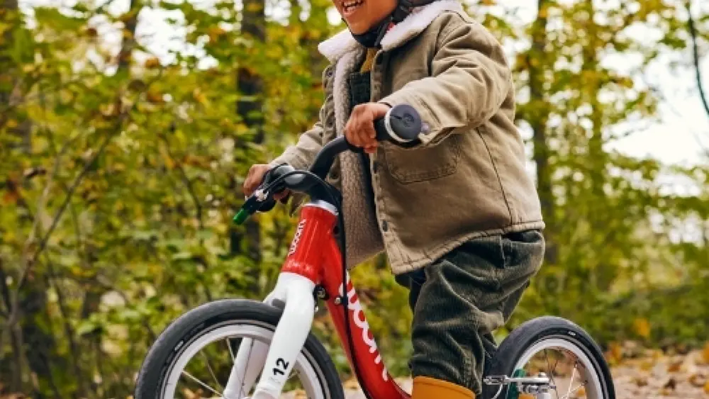 Ein Kind testet ein Laufrad der Marke "woom" in der woom bike area des Ravensburger Spieleland.