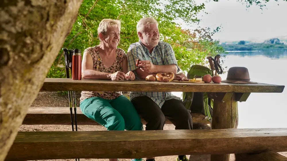 Ein Ehepaar genießt eine Pause am Ufer des Mindelsees.