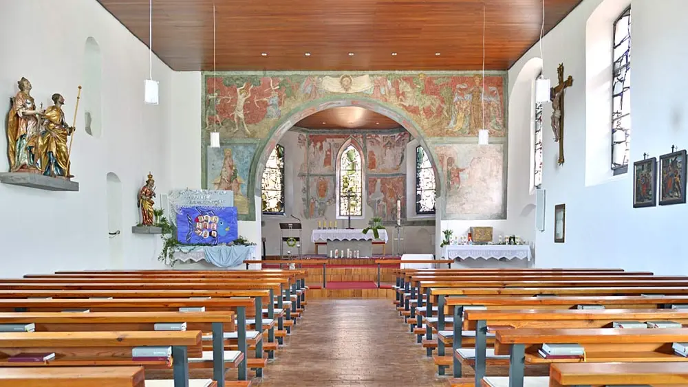 Blick in den Innenraum der Pfarrkirche St. Jakobus in Reuthe mit Altar und Wandmalerei