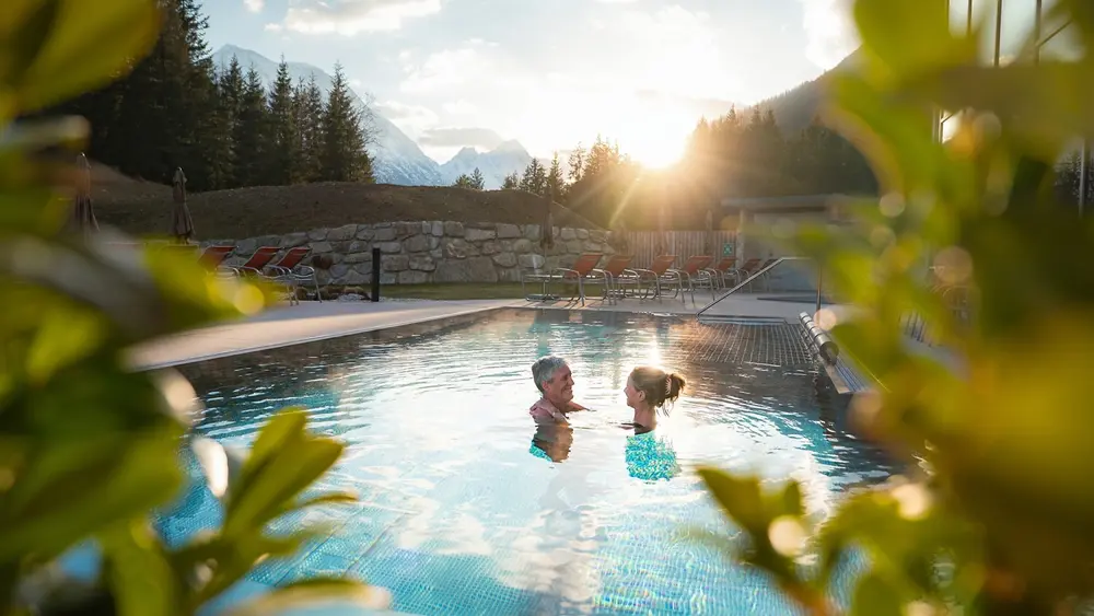 Paar im Outdoor-Pool bei Sonnenuntergangsstimmung