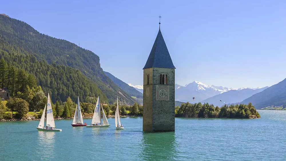 Turm von Altgraun im Reschensee mit Segelbooten