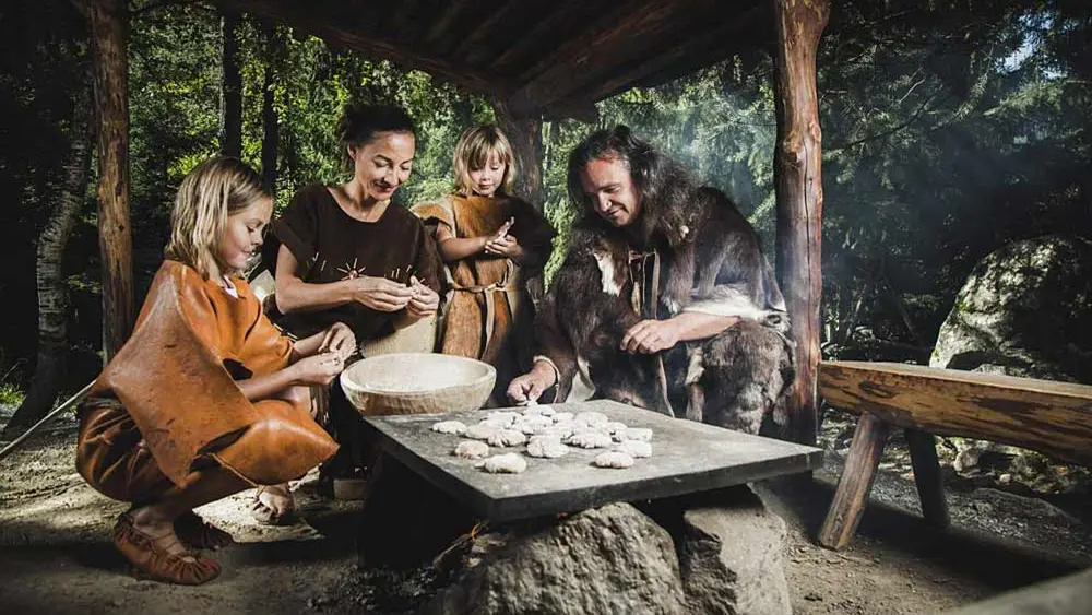 Familie beim steinzeitlichen Brotbacken im Ötzidorf