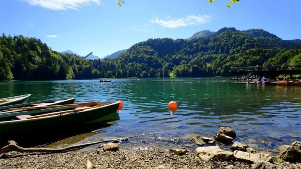Boote am Ufer des Freibergsees, im Hintergrund die Heini-Klopfer-Skisprungschanze