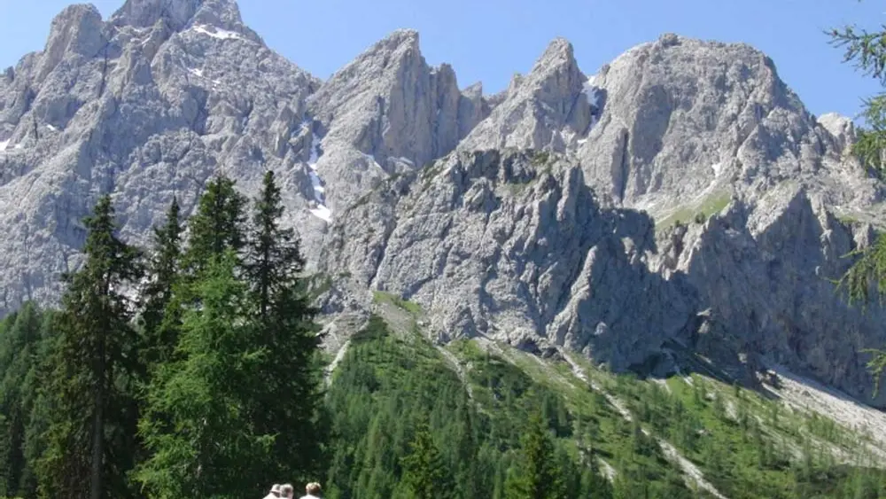 Wanderer auf einer Wiese mit den Drei Zinnen im Hintergrund