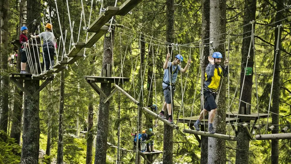 Personen auf dem Parcours zwischen den Bäumen im Hochseilpark Saalbach Hinterglemm