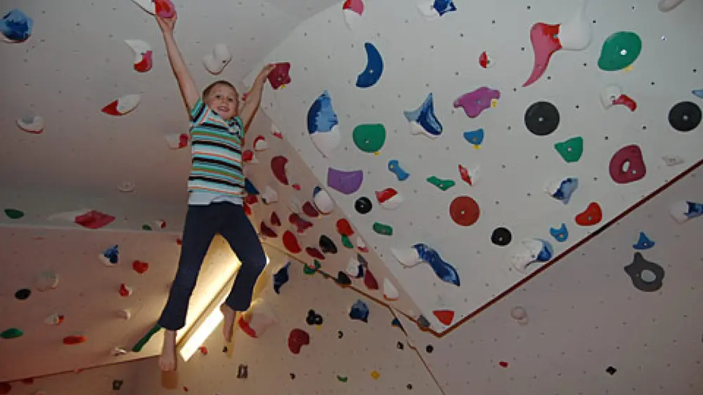 Kind hängt an einer Kletterwand im Sportpark Kitzbühel