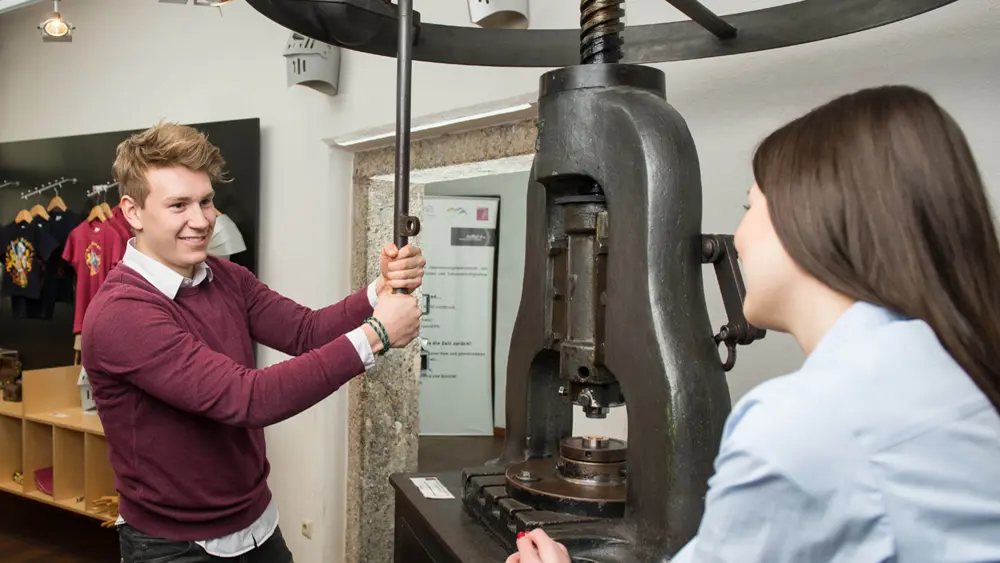 Paar an einer Münzpresse im Museum Münze Hall