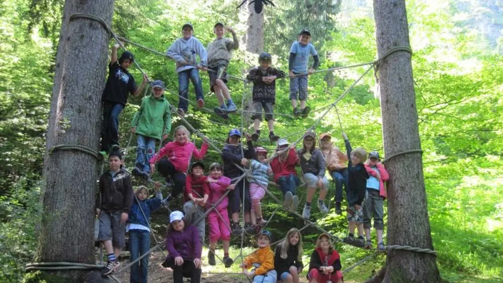 Eine Gruppe Kinder sitzt in einem Kletternetz im Walderlebniszentrum Ziegelwies