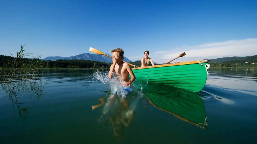 Frau im Ruderboot und Kind im Wasser auf dem Turnersee bei St. Kanzian