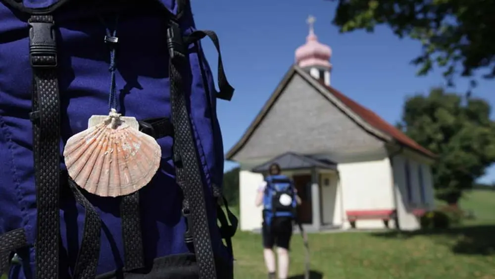Pilger auf dem Bayerisch-Schwäbischen Jakobsweg, im Hintergrund die Wendelinskapelle in Niederstaufen