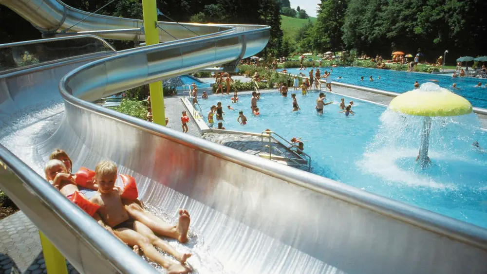Blick auf die Schwimmbecken und die Wasserrutsche des Starzlachauenbads in Wertach