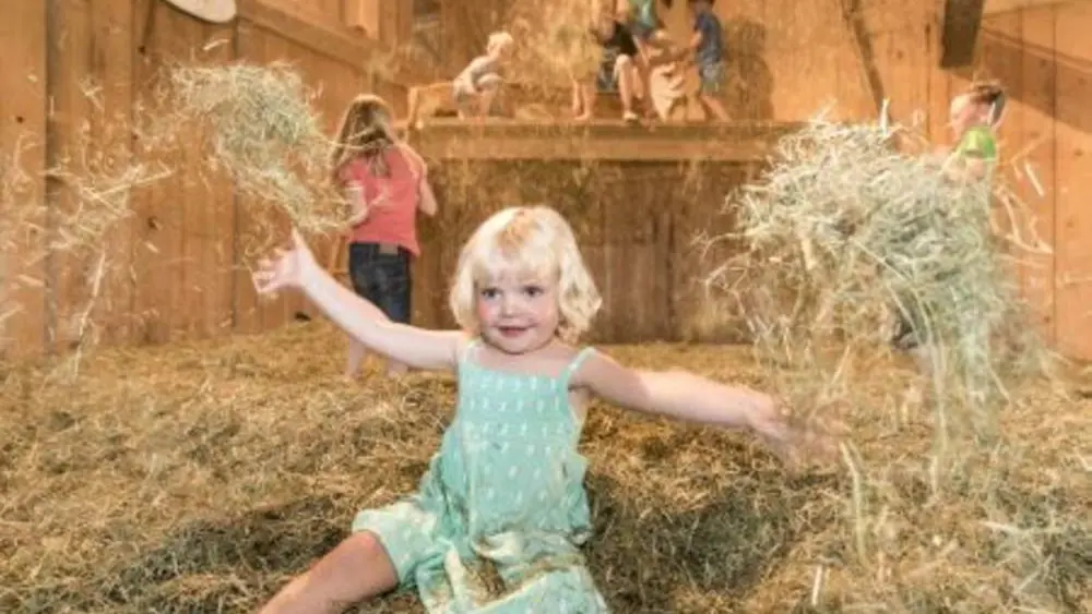 Kinder beim Spielen im Heu auf dem Bauernhof des Allgäuer Bergbauernmuseums