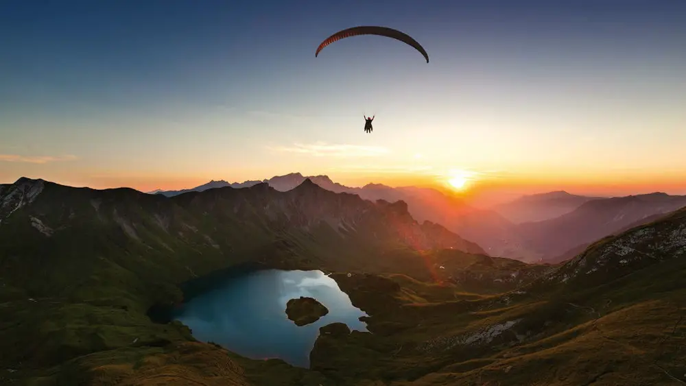 Ein Tandemgleitschirmflieger im Sonnenuntergang am Nebelhorn in Oberstdorf