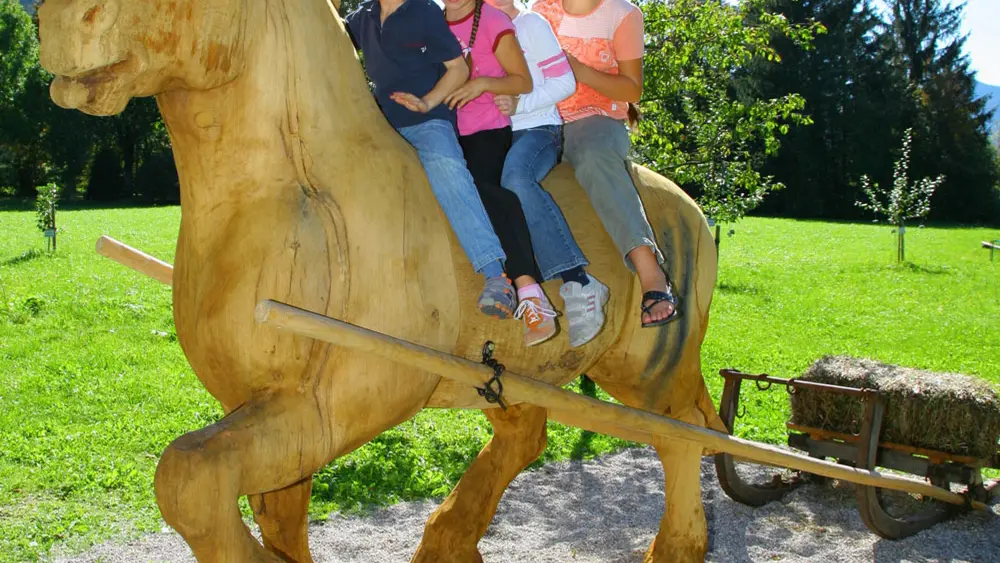 Kinder auf dem Holzpferd neben dem Museum im Gsotthaber Hof in Rottach-Egern
