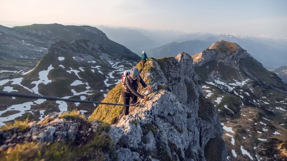 Zwei bergsportbegeisterte Frauen genießen die Morgenstimmung am Klettersteig Rosskopf im Rofangebirge.