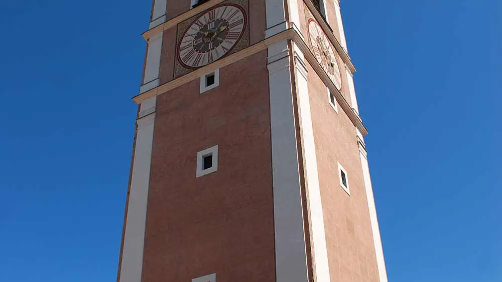 Blick von unten auf den langen Kirchturm der Pfarrkirche Kastelruth