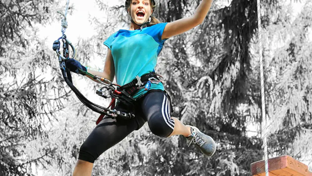 Frau beim Sprung im Kletterpark Lienz