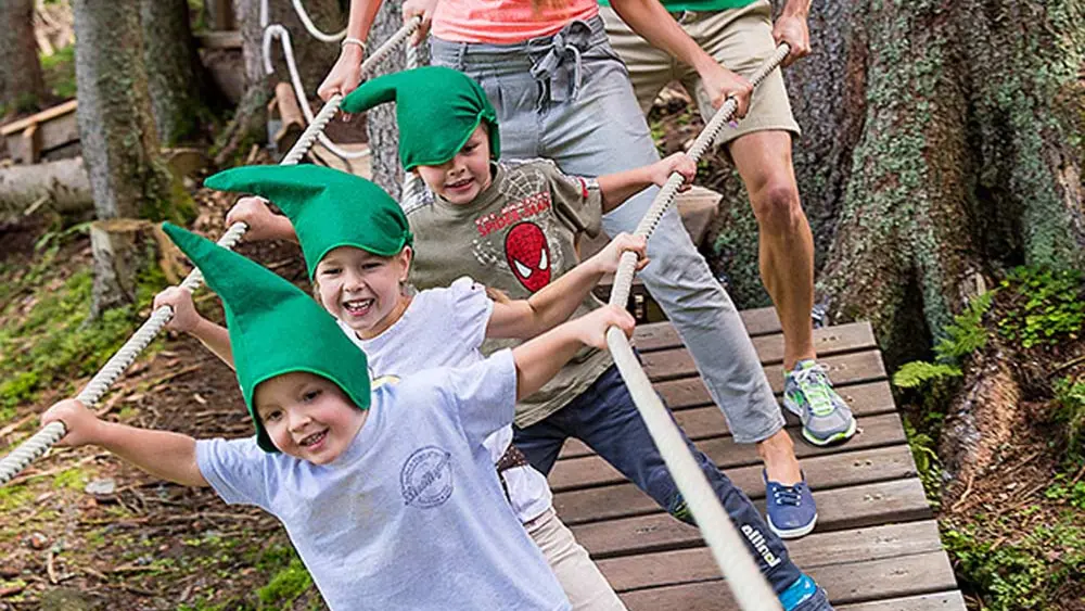 Familie mit grünen Zipfelmützen auf dem Baumzipfelweg in Hinterglemm