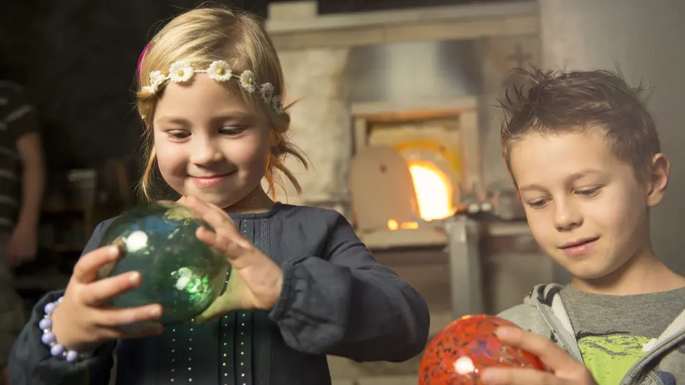Kinder mit Glaskugeln in der Kisslinger Glasbläserei in Rattenberg