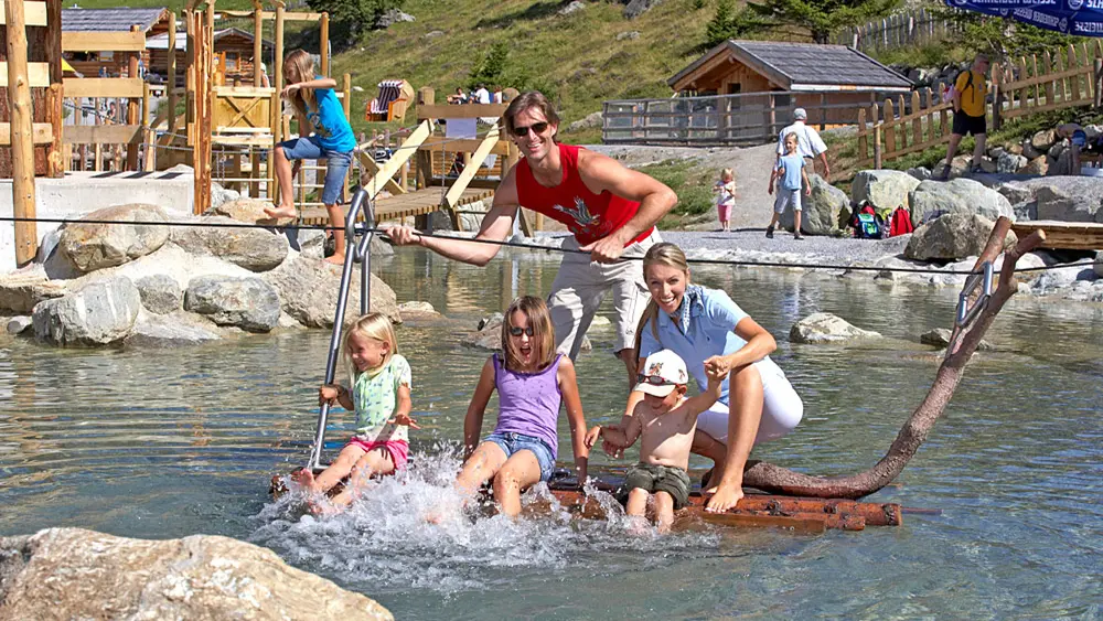Familie beim Planschen im Wildbach des Wasserspielparks Murmliwasser in Serfaus