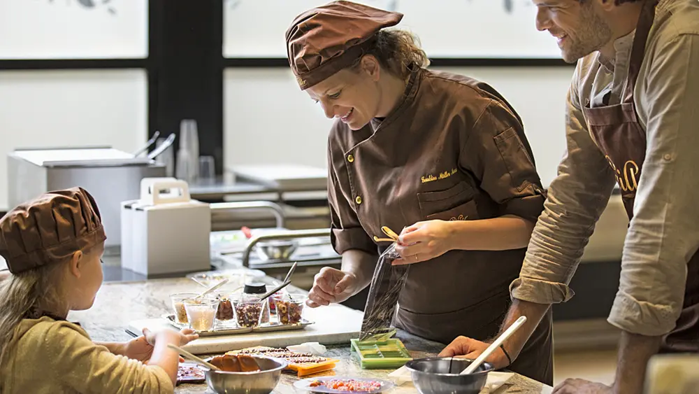 Chocolatiers bei der Pralinenherstellung im Atelier du Chocolat der Maison Cailler in Broc
