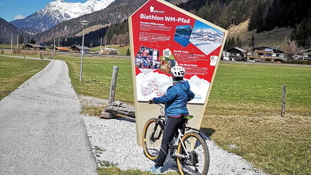 Bikerin vor einer Station des Biathlon-WM-Pfads