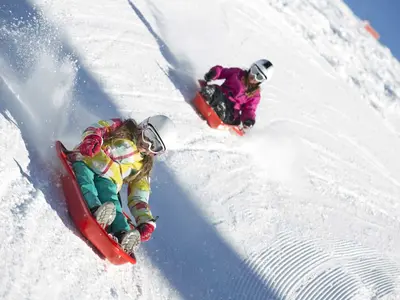 Kinder beim Rodeln mit Rutschwannen in Alpe d'Huez © Laurent Salino / Alpe d?Huez Tourisme