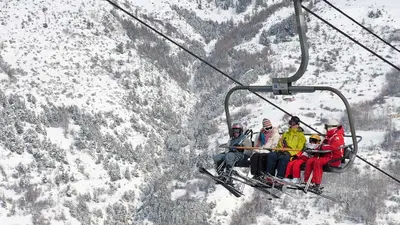 Vier Skifahrer in einem Sessellift in Serre Chevalier