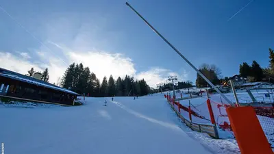 Piste mit Skifahrer und Beschneiungsanlage