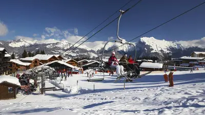 Skifahrer im Sessellift neben der Piste