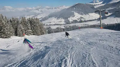 Zwei Skifahrer auf der Piste mit Sessellift