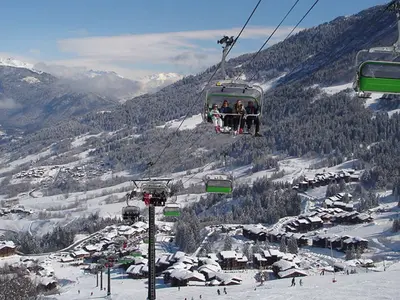 Sessellift mit Skifahrern über dem Skigebiet © OT Valmorel