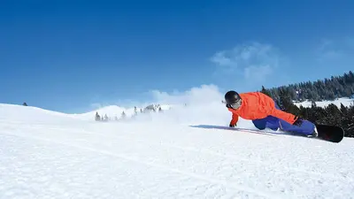 Snowboarder kurvt über die Piste in Grasgehren