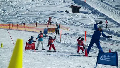 Skilehrer mit Kindernbeim Slalomfahren in der Skischule Grasgehren