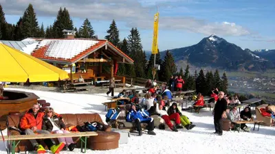Menschen beim Sonnenbaden auf Sofas vor der Hochbichlhütte am Ofterschwanger Horn