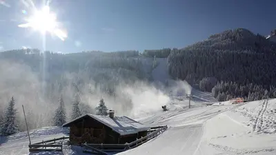 Blick auf Hütte und Schneekanone im verschneiten Skigebiet Alpspitzbahn Nesselwang