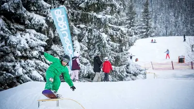 Kind mit Snowboard grindet über Rail im Kidspark Nesselwang