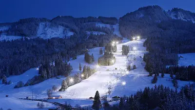 Blick auf die für den Nachtskilauf beleuchtete Piste in Nesselwang