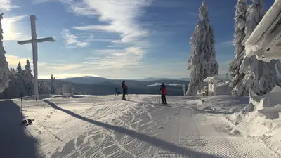 Verschneiter Almberg mit Gipfelkreuz