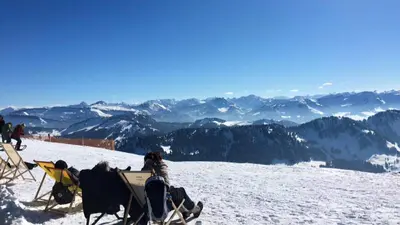 Skifahrer im Liegestuhl vorm Bergpanorama