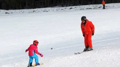 Vater mit Kind auf der Piste im Skigebiet Kreuzberg